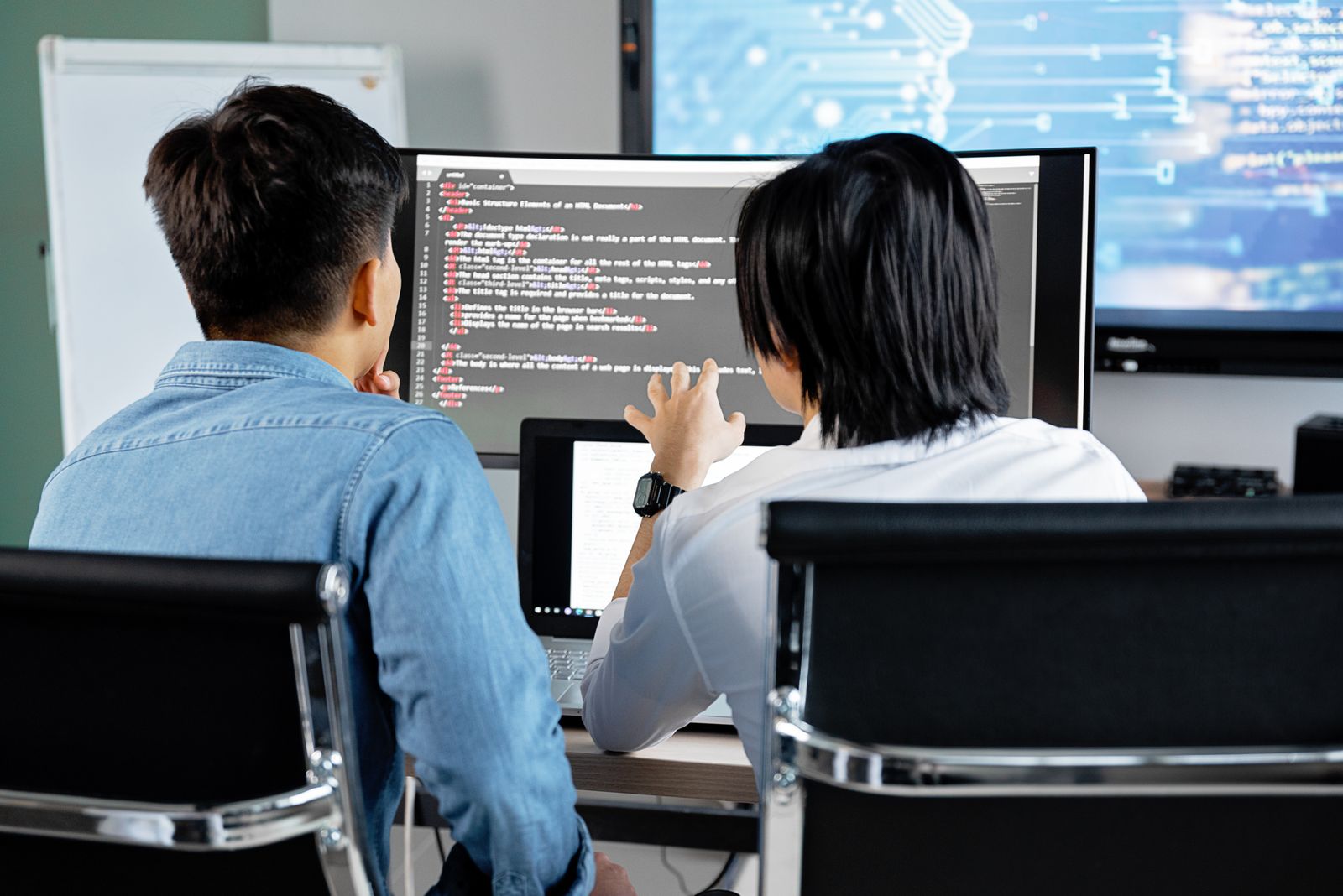 Two SID engineers discussing code on screen at the HCMC studio